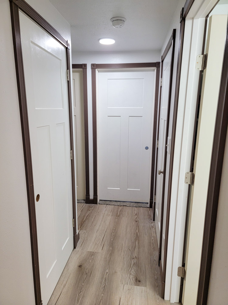 Corridor with multiple doors leading to different rooms, and a laminate floor
