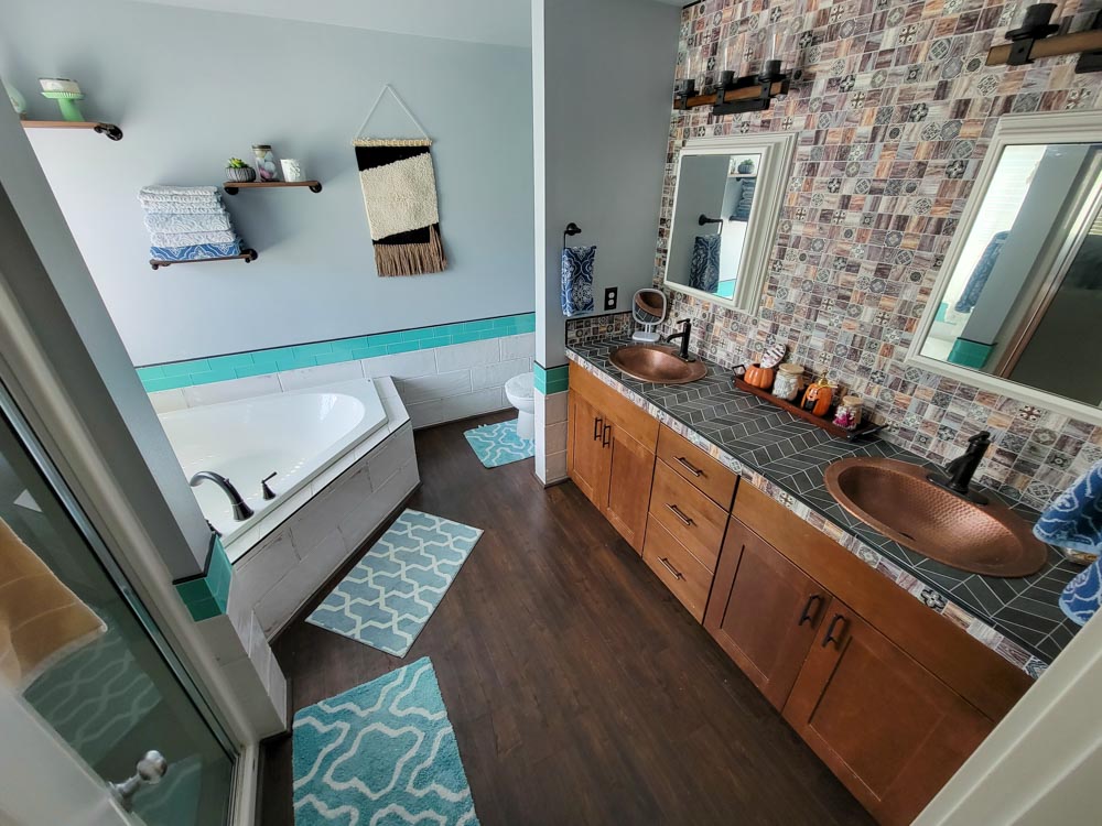 A compact bathroom with hardwood floor, a bathtub in one corner, tiled countertop and backsplash of the wash area