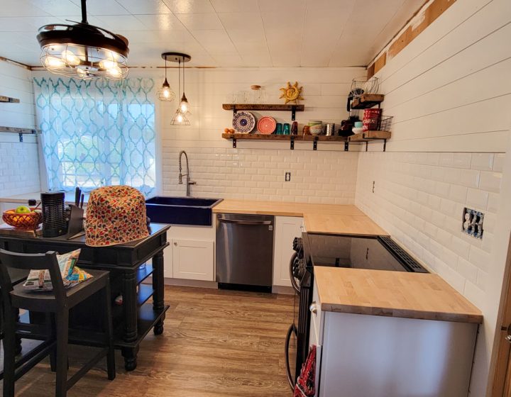A kitchen remodeled with newly painted wall, installed tile backsplash, wall-mounted shelves, and upgraded countertops