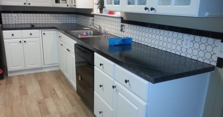 Washing and working area in the kitchen with black appliances, a marble countertop, white cabinets, and a tiled backsplash